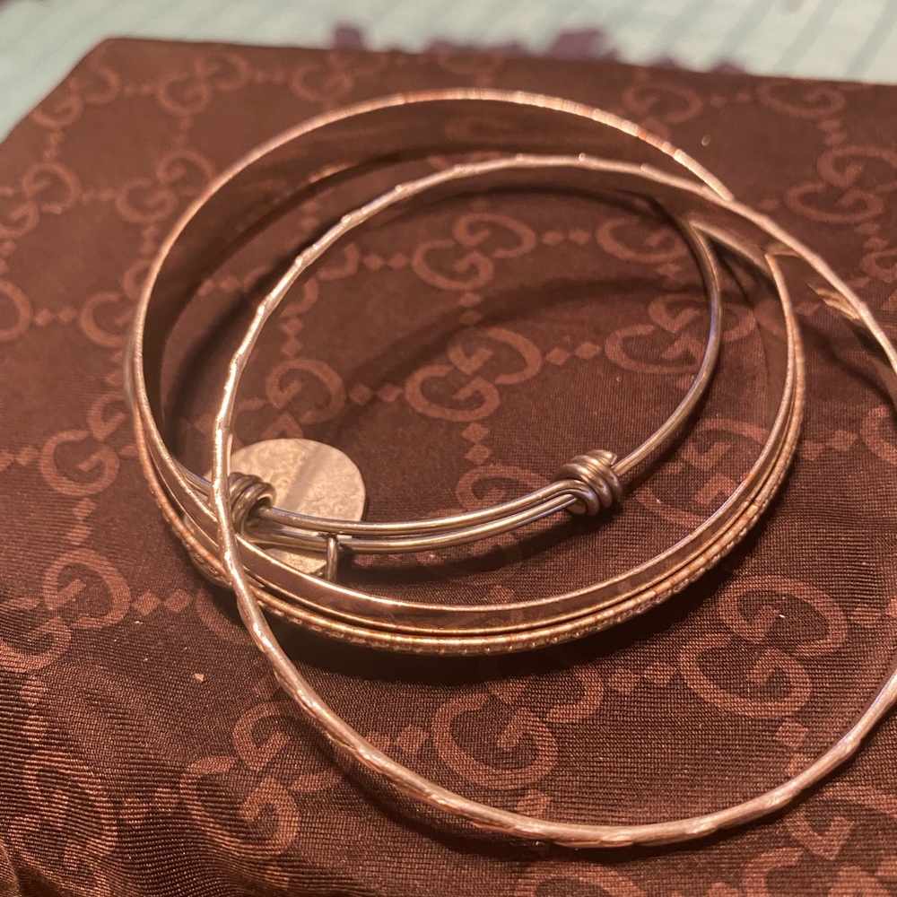 4 Silver bracelets, one with a charm.